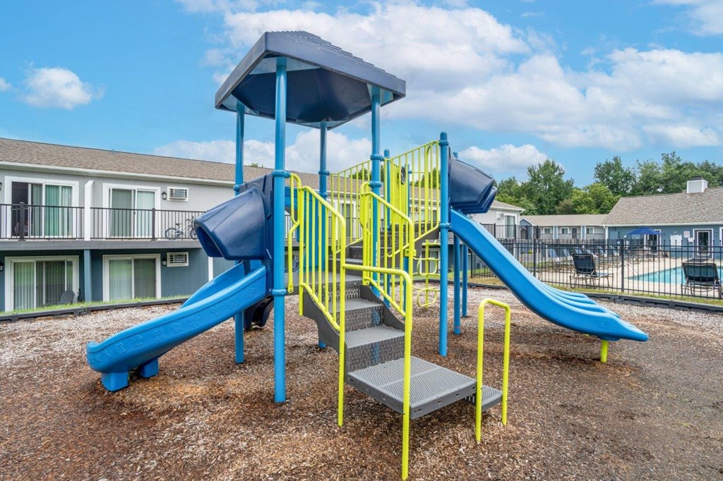 A playground with a blue and yellow slide.