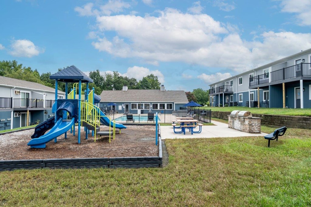 A playground with a blue slide and picnic table.