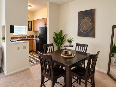 A dining room with a table set for two and a framed picture on the wall.
