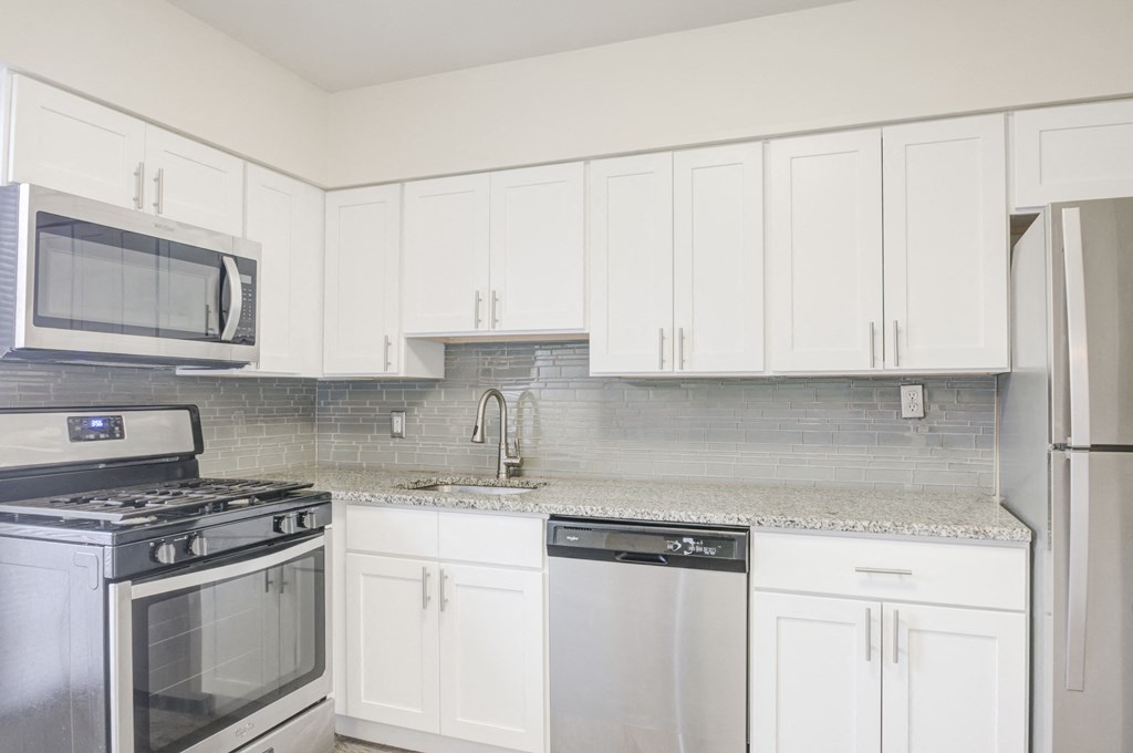 a kitchen with white cabinets and stainless steel appliances