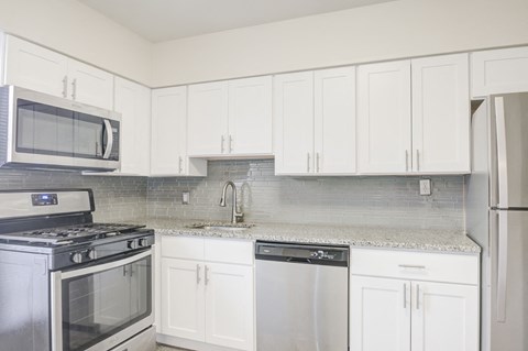 a white kitchen with stainless steel appliances and white cabinets