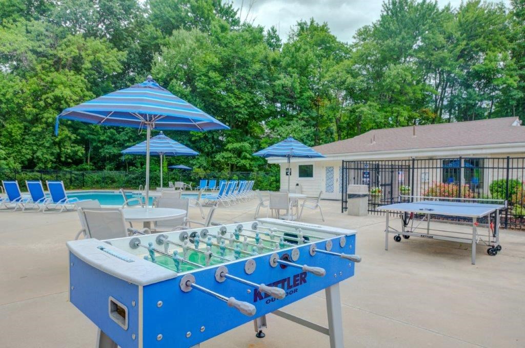 a foosball table in a pool area with chairs and umbrellas