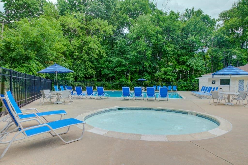 a swimming pool with blue chairs and umbrellas and a fence