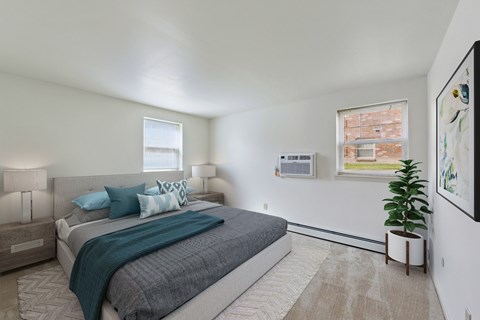 A bedroom with a large bed and a potted plant.