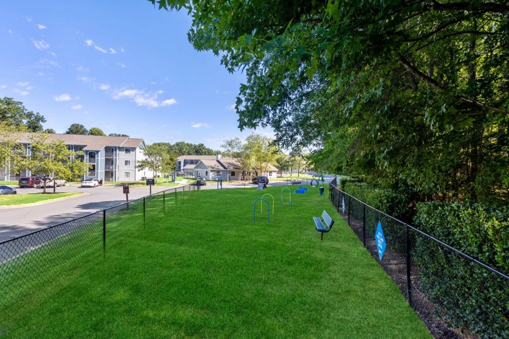 a park with benches on the grass next to a fence