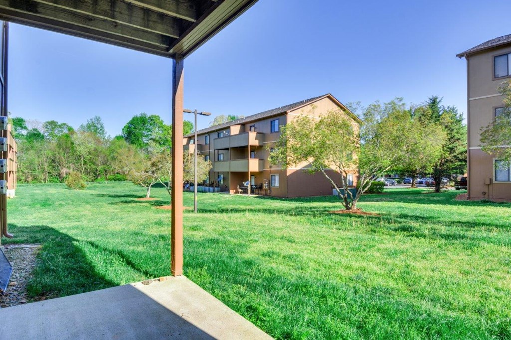 the view of an apartment building from a porch with grass and trees