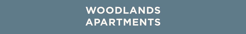 The image displays the words "Woodlands Apartments" in a large, bold font.