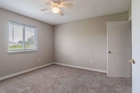 A room with a ceiling fan and a window with blinds.