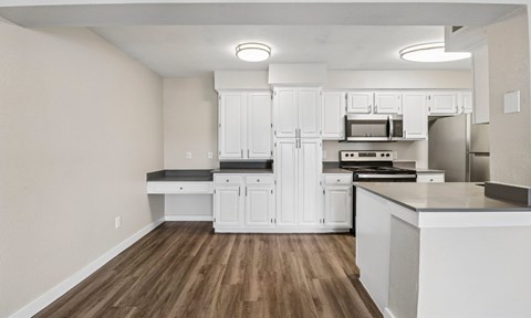 A kitchen with white cabinets and a wooden floor.