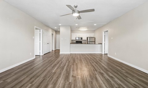 A spacious room with a ceiling fan and wooden flooring.