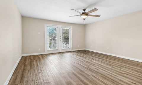 A room with a ceiling fan and sliding glass doors.