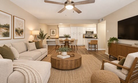 A living room with a beige sofa, a coffee table, and a flat-screen TV.