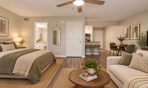 A bedroom with a bed, a couch, a table, and a ceiling fan.