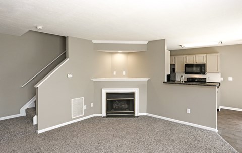 A living room with a fireplace and a staircase.