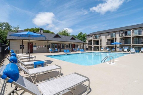 A pool area with sun loungers and a building in the background.