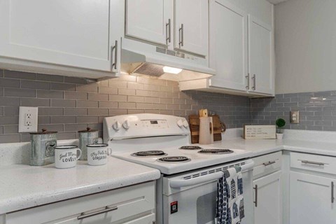 A kitchen with white cabinets and a white stove top oven.
