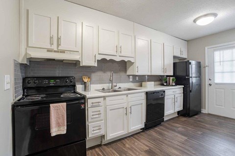 A kitchen with black appliances and white cabinets.
