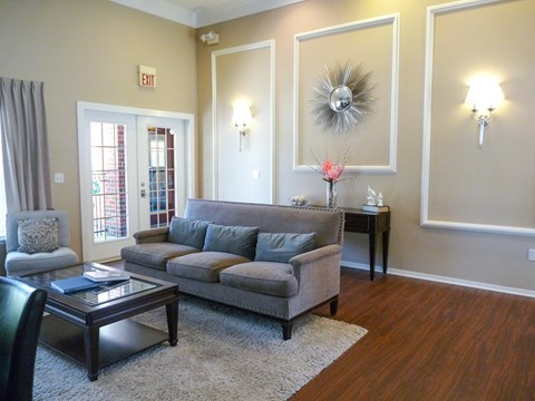 A living room with a grey couch, a coffee table, and a glass door.