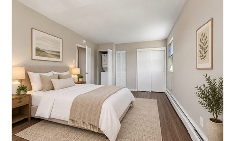 A bedroom with a large bed and a plant on the side table.