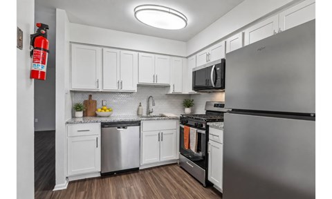 A modern kitchen with white cabinets and stainless steel appliances.