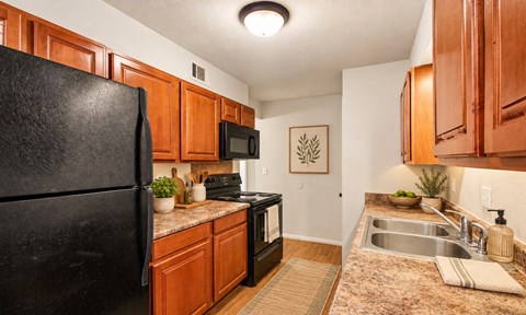 A kitchen with black appliances and wooden cabinets.