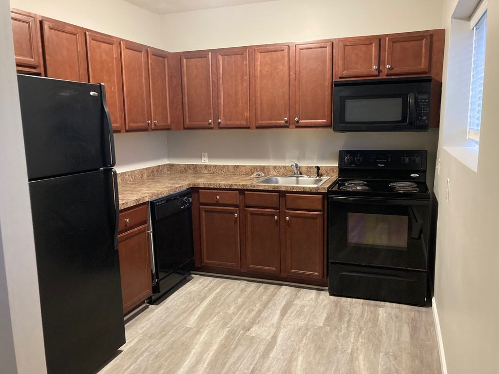 A kitchen with black appliances and brown cabinets.