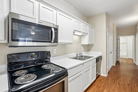 A kitchen with a black stove top oven and white cabinets.
