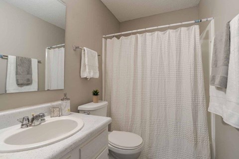 A white bathroom with a toilet, sink, and shower curtain.