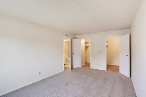 A large empty room with carpeted floor and white walls.
