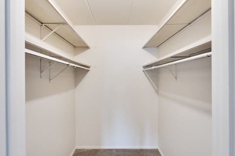 Empty white walk in closet with shelves.
