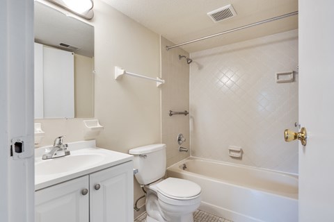 A white bathroom with a toilet, sink, and bathtub.