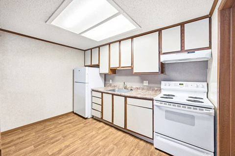 A kitchen with white appliances and wooden cabinets.