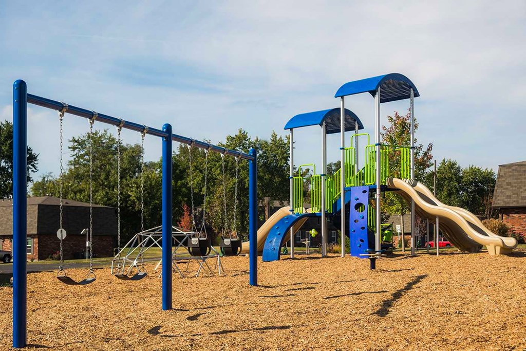 A playground with a blue swing set and a yellow slide.