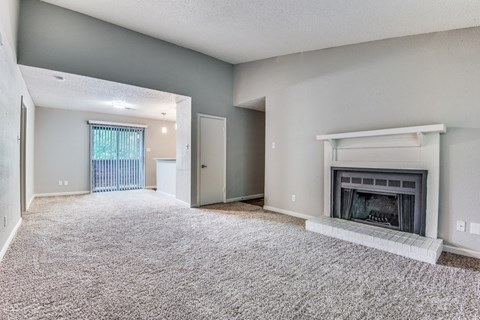 A spacious living room with a fireplace and a carpeted floor.