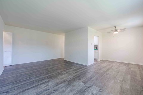 A room with a ceiling fan and wooden flooring.