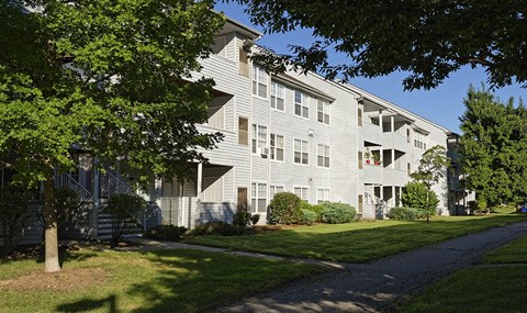a large white apartment building with a sidewalk in front of it
