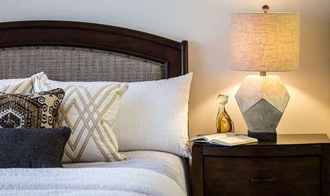 a bedroom with a bed and a night stand with a lamp