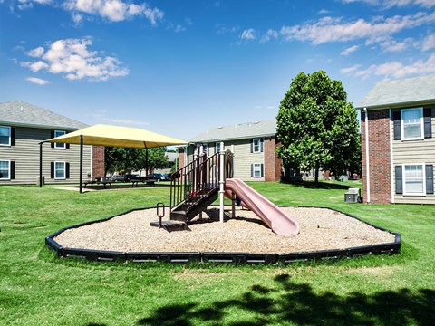 A playground with a slide and a yellow umbrella.