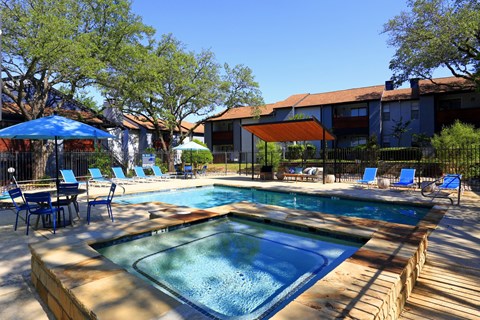 A pool with a blue umbrella and chairs around it.
