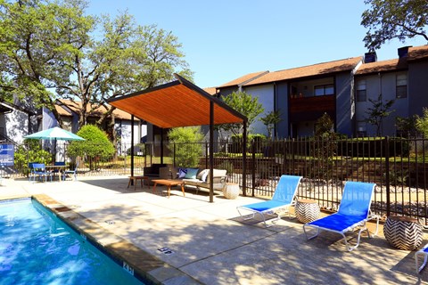 A pool with a sun lounger and a table in front of a building.