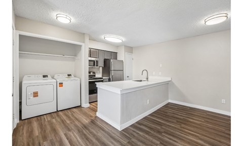 A kitchen area with a white countertop and wooden flooring.