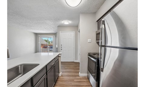 A kitchen with a stainless steel refrigerator and a white door.