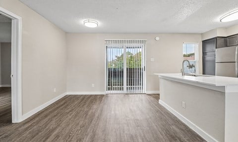 A room with a sliding glass door and wooden flooring.
