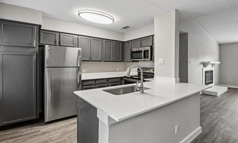 A modern kitchen with stainless steel appliances and a white countertop.