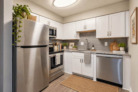 A modern kitchen with a stainless steel refrigerator and white cabinets.