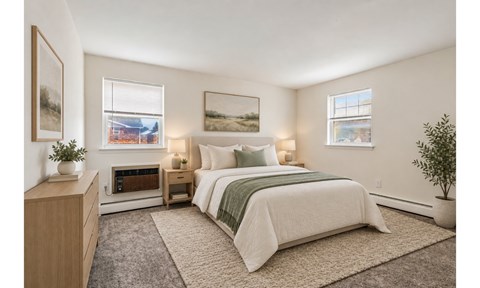 A bedroom with a large bed and a small table with a plant on it.