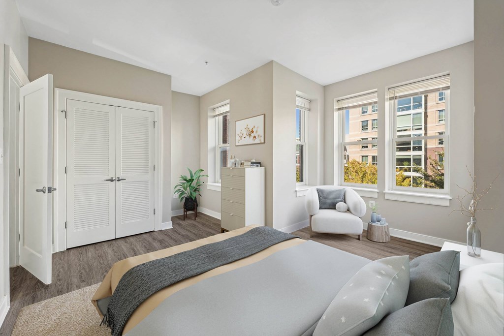 A bedroom with a large bed and a window overlooking a cityscape.