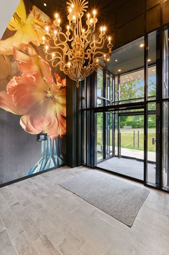 A large chandelier hangs over a grey rug in a room with a large mural of flowers on the wall.