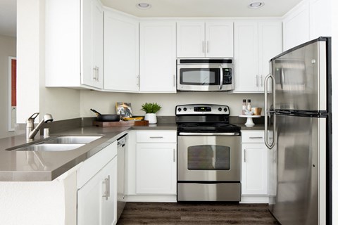 A modern kitchen with white cabinets and stainless steel appliances.