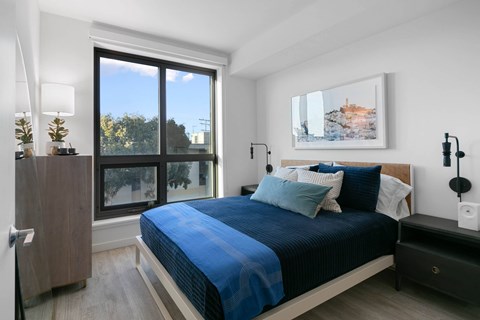 A bedroom with a large bed and a painting on the wall.